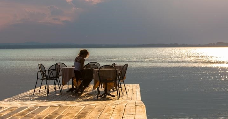 Tisch auf einem Steg am See bei Sonnenuntergang