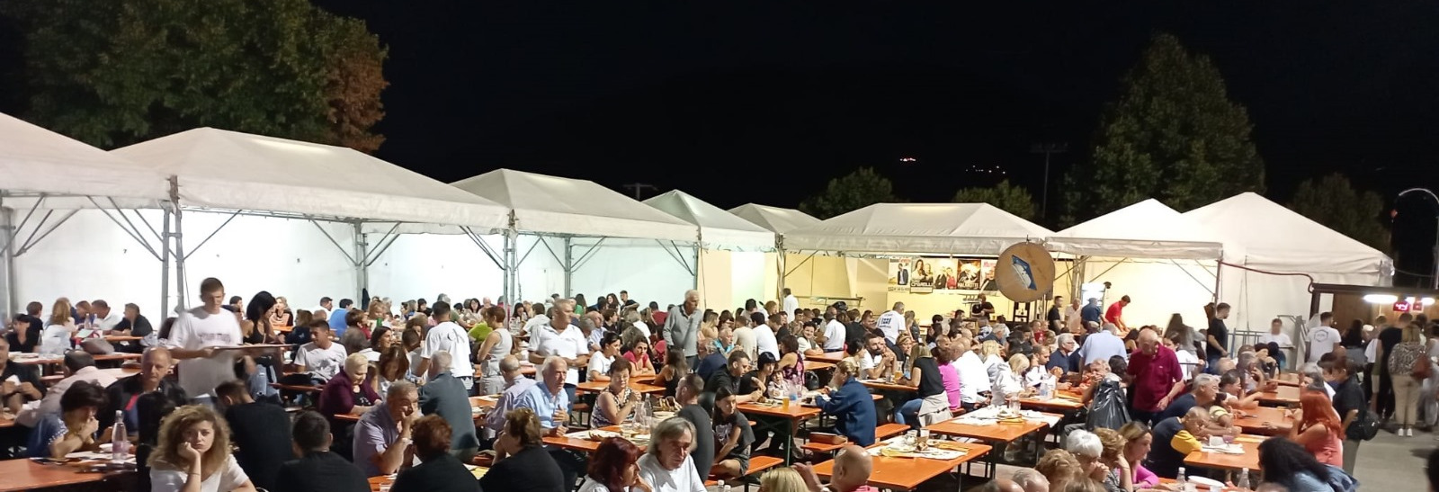 Photograph of an evening at the festival with crowded tables of people having dinner.