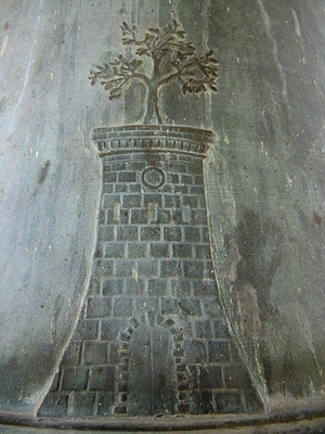 Bas-relief on a bronze bell depicting a stone tower topped with a stylized olive tree