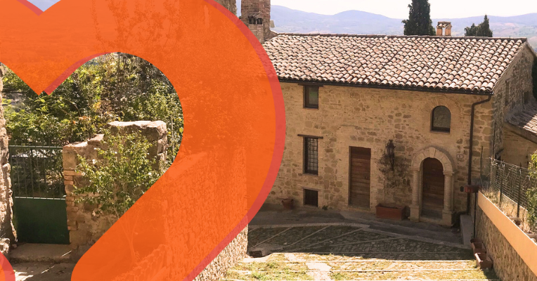 Glimpse of the medieval village of Gualdo Cattaneo, with stone houses lining a sloping alley.