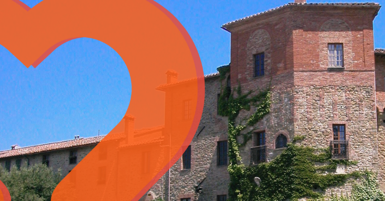 Historic buildings of Paciano with stone and brick walls, featuring windows and green climbing plants under a blue sky.