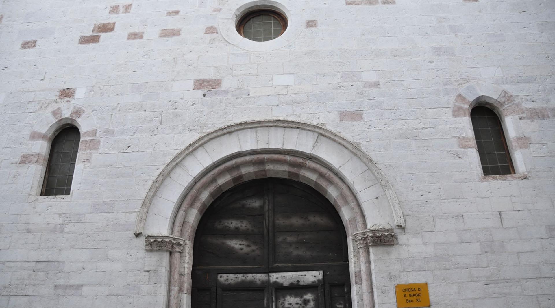 Facciata in pietra della chiesa di San Biagio, con portale ad arco, finestre strette e oculo centrale.