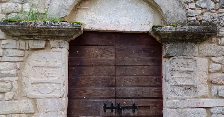 Entrance portal of a stone church, with walls incorporating reused materials from the Roman period.