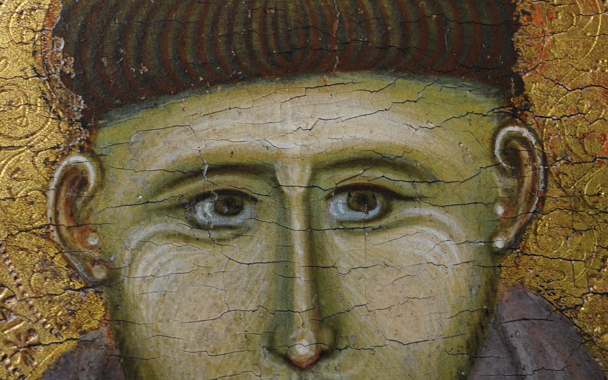 Gros plan d’un visage sacré représentant des yeux peints sur panneau avec fond doré et craquelures visibles.