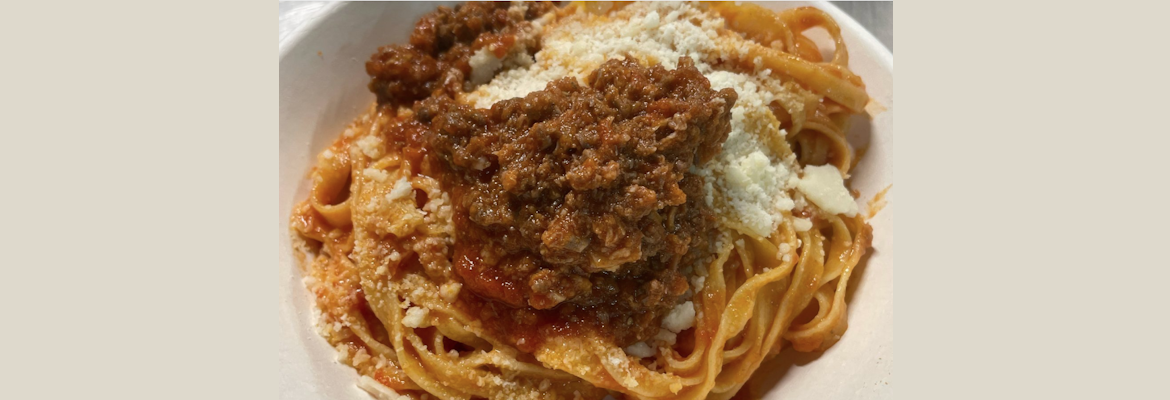 Piatto di tagliatelle fresche condite con sugo d’oca e una spolverata di formaggio grattugiato.