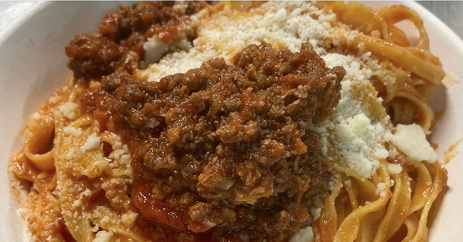 Assiette de tagliatelles fraîches accompagnées d’un ragoût d’oie et d’une pincée de fromage râpé.