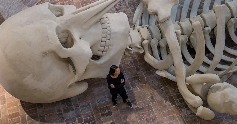 Scheletro gigante installato in una chiesa sconsacrata, tra luci soffuse e architettura in mattoni