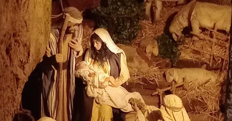 Scène de la Nativité avec Marie tenant l’Enfant Jésus dans ses bras, Joseph à ses côtés, et plusieurs personnages agenouillés en adoration, entourés d’animaux et d’un décor rural. 