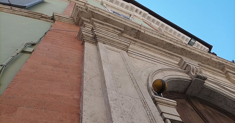 Low-angle view of the monumental portal of Palazzo Conestabile Della Staffa, with stone mouldings and historic façade.
