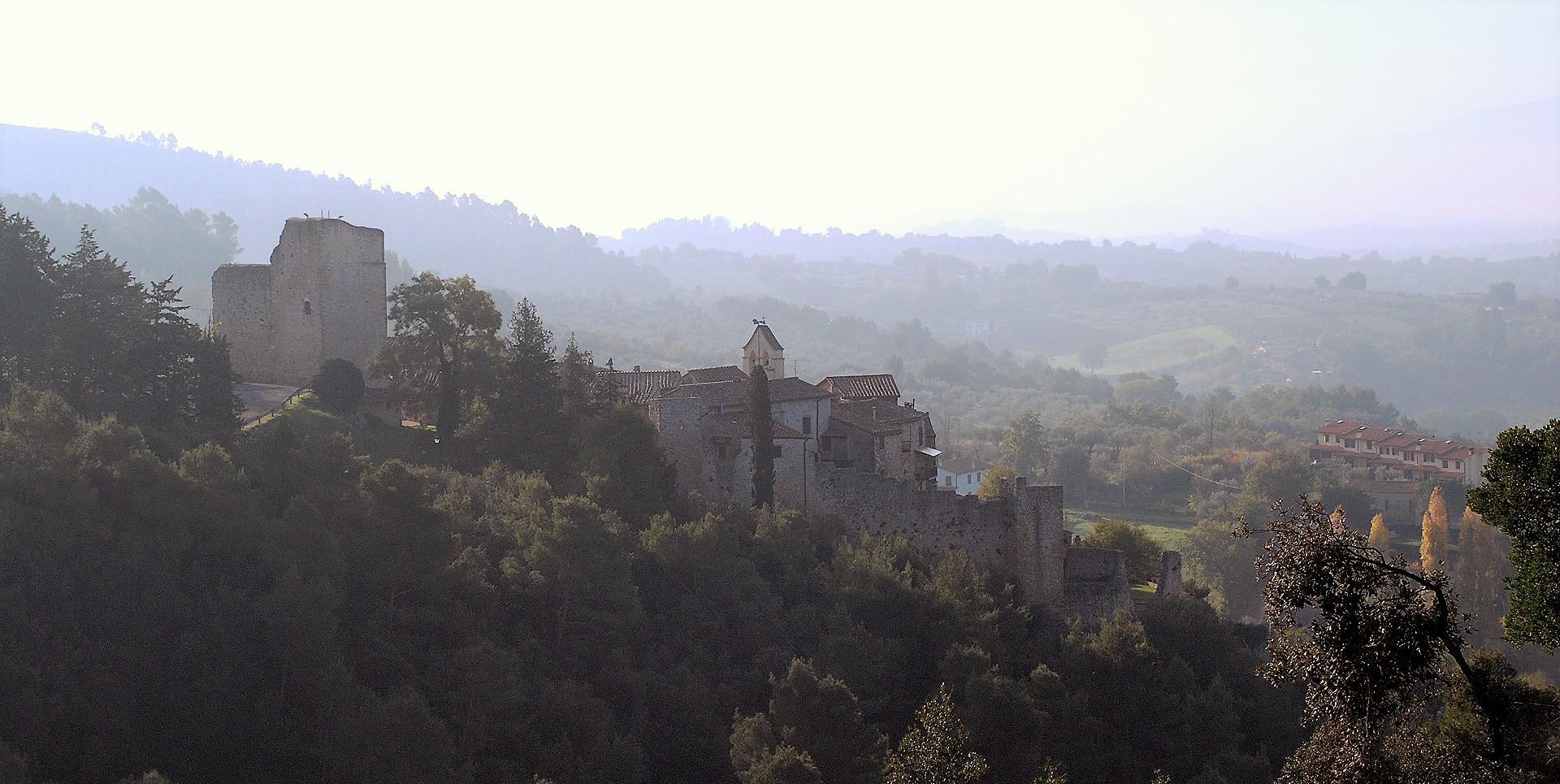 Veduta del Castello di Poggio di Otricoli, con mura in pietra e torre, immerso in un paesaggio collinare.