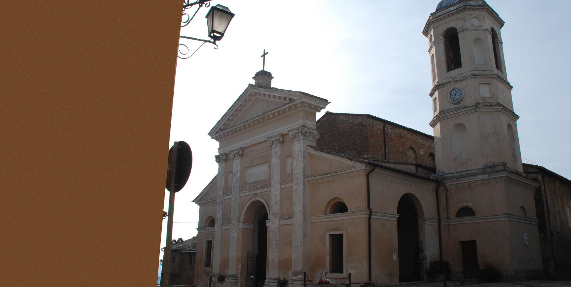 Veduta laterale della Collegiata con facciata classica e campanile, affacciata su una piazza del borgo.