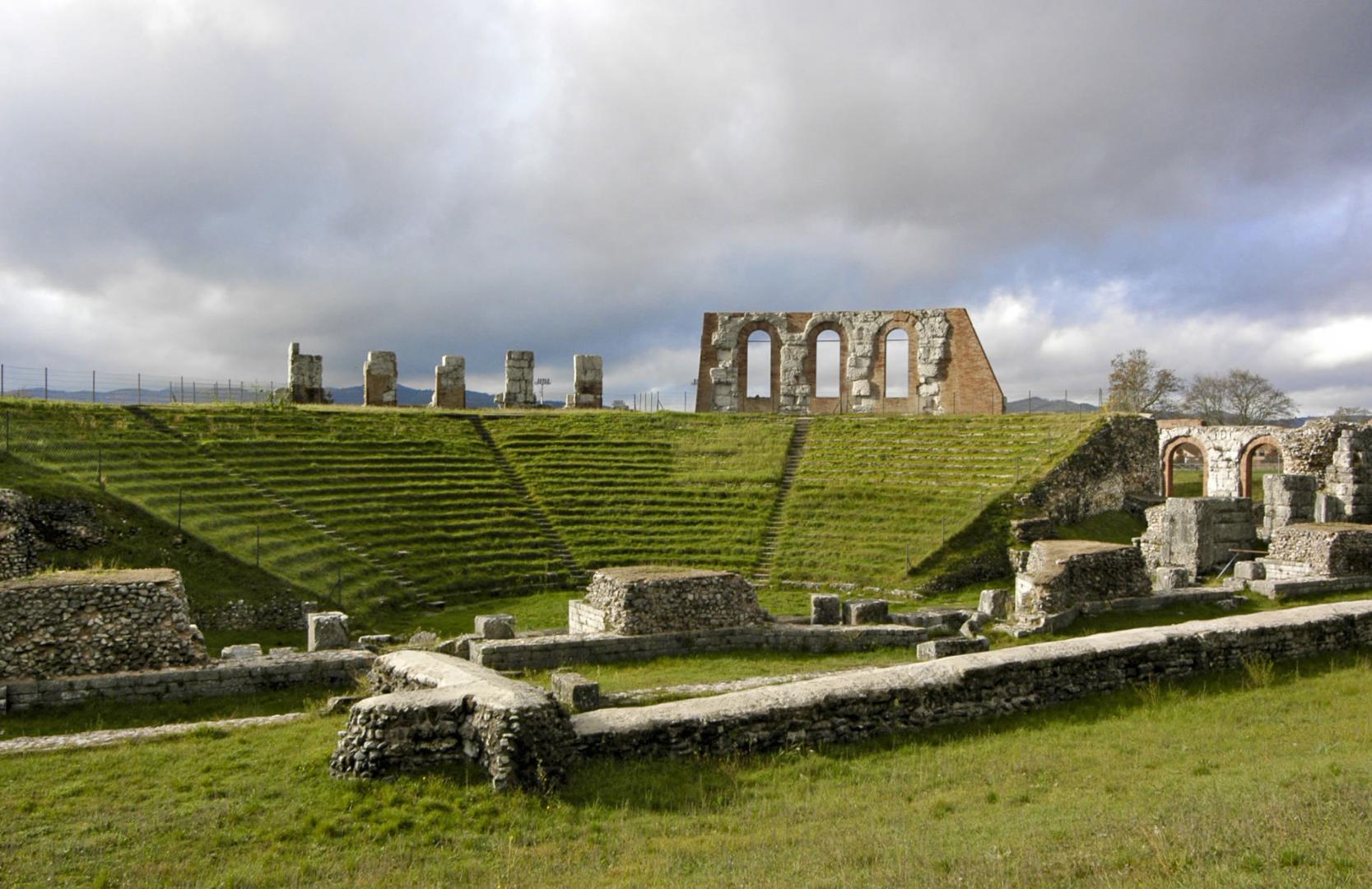 View from the orchestra of the interior of the Roman theatre of Gubbio with the cavea covered by the steps and, at the back, part of the upper archway