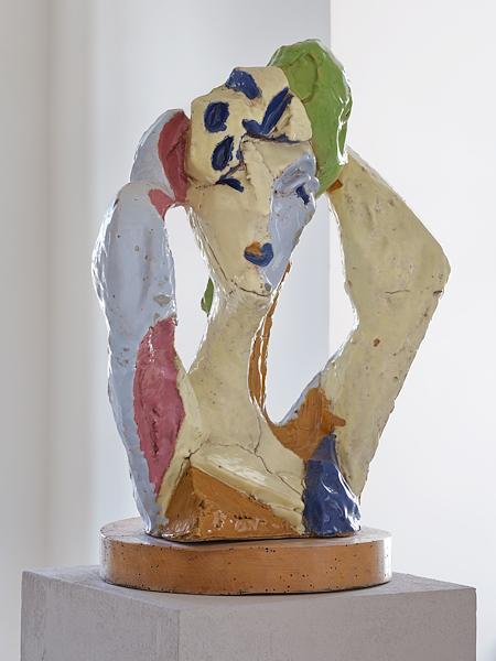Scultura figurativa in ceramica policroma con forme umane stilizzate nei toni del giallo, azzurro, rosa, verde e blu.