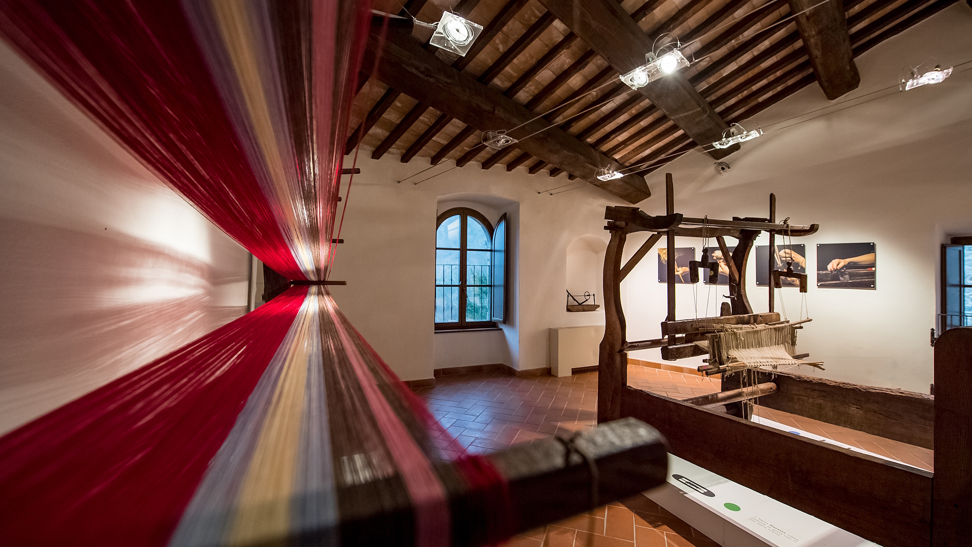 Exhibition hall of the Hemp Museum featuring an antique loom and warping frame with threads of various colors stretched across the pegs in the foreground