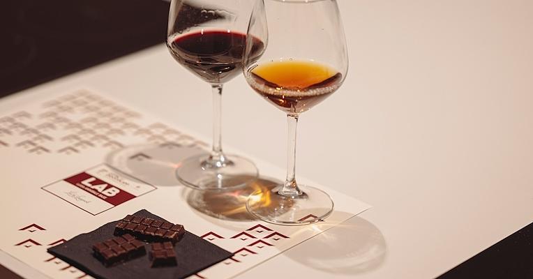 Two glasses of wine next to chocolates on a table.