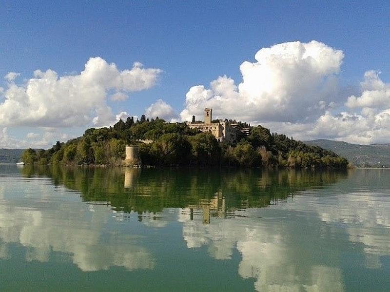 View of Isola Maggiore on Lake Trasimeno under a cloudy sky.