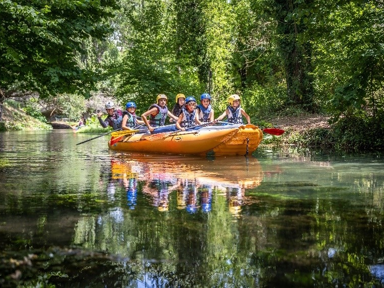 Group of people on an inflatable raft during a rafting excursion along the Nera River, surrounded by vegetation.