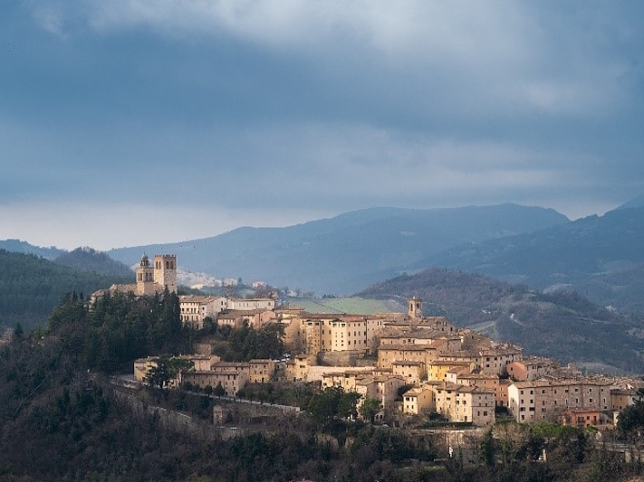 View of Nocera Umbra perched on a hill, with the village and its medieval towers surrounded by a hilly landscape.