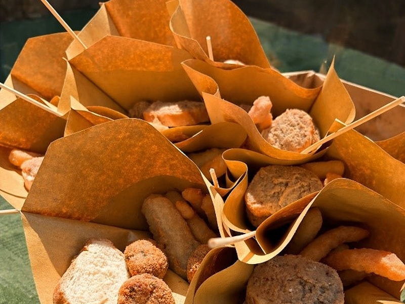 Paper cones filled with fried lake fish and Umbrian street food bites, arranged on a green tablecloth.