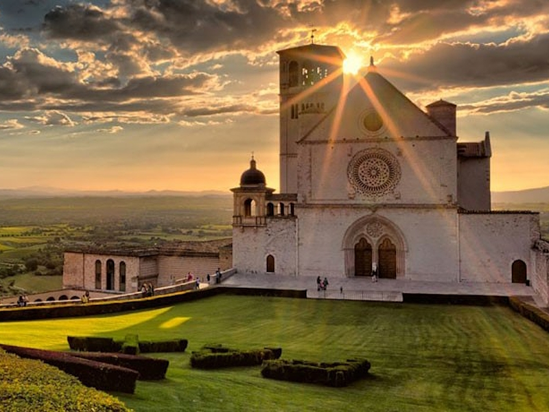 View of the Basilica of Saint Francis in Assisi illuminated by the light of the sunset.