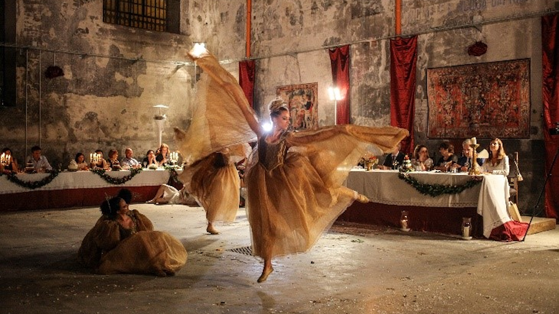 Dancers in period costumes perform during the “Gareggiare dei Convivi” event of the Giostra della Quintana in Foligno, in front of an audience seated at tables.