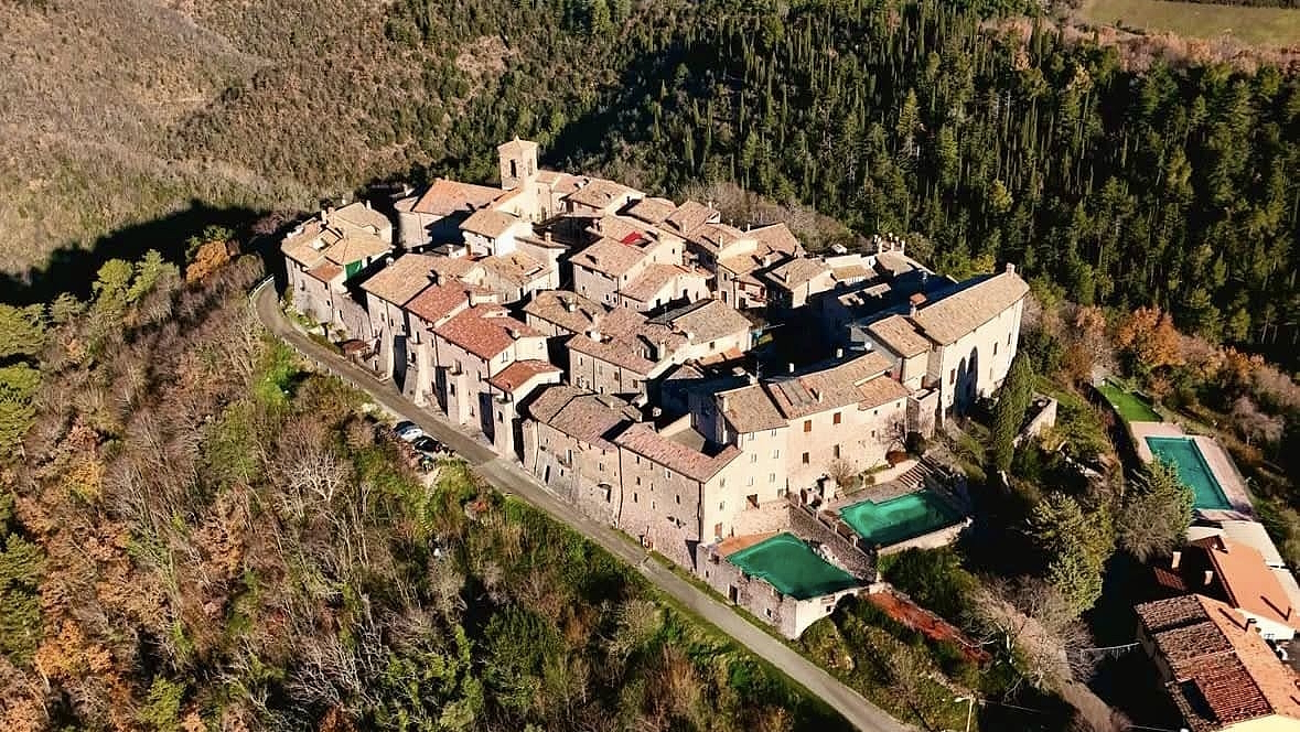 Veduta aerea del castello medievale di Macerino sui Monti Martani, immerso nei boschi umbri