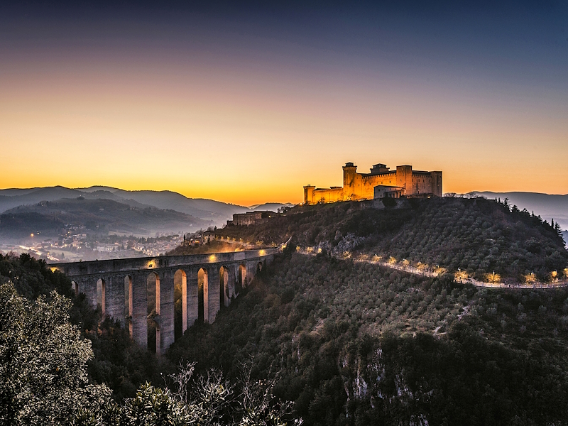 La Rocca Albornoziana di Spoleto al tramonto sul colle, con il Giro della Rocca da cui parte il Ponte delle Torri