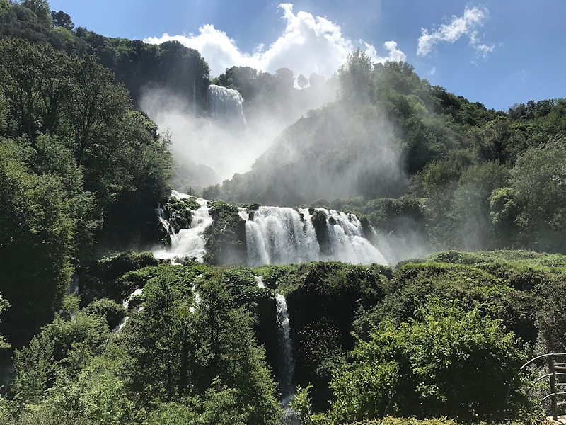 La Cascata delle Marmore immersa nel verde, con salti d’acqua tra la vegetazione e nebbia generata dalla forza della cascata