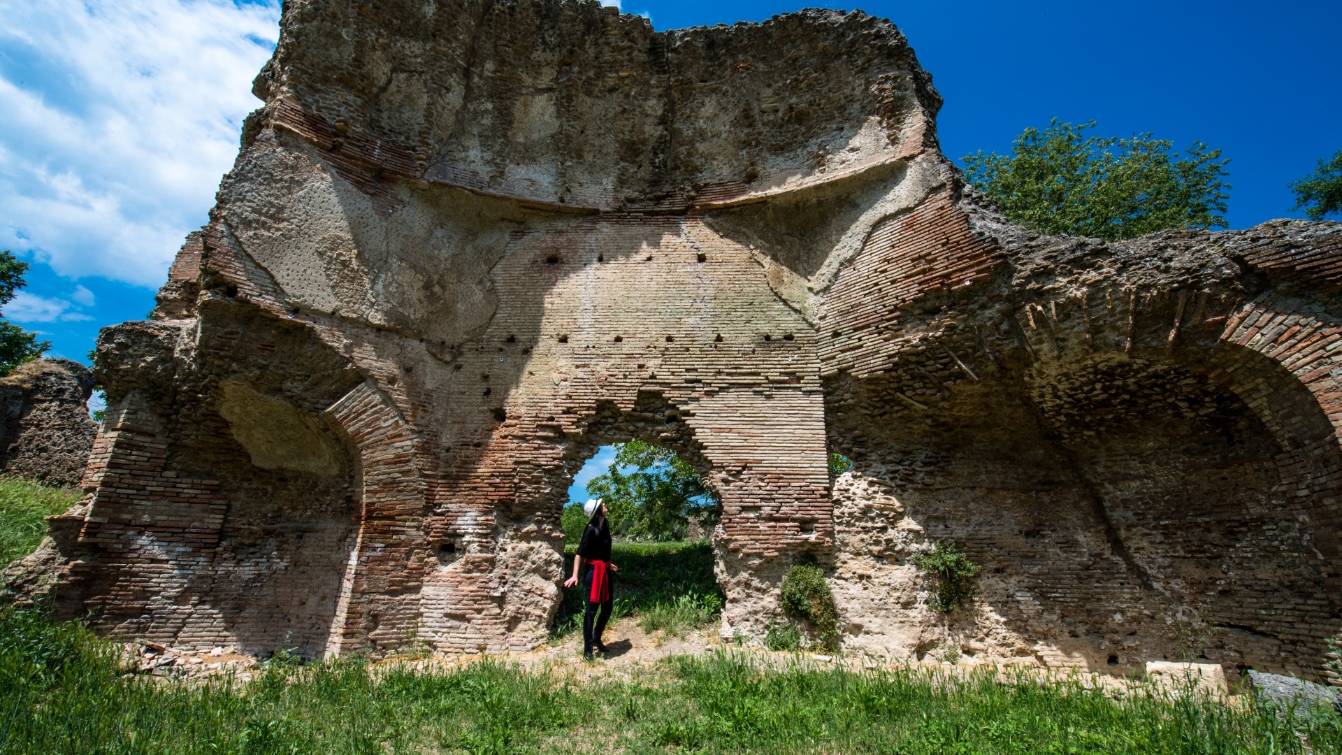 Ruins of the Roman Baths of Ocriculum with imposing brick walls and a person standing at the centre, highlighting the scale of the monument.