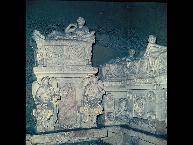 Interior of the Volumni Hypogeum with Etruscan stone funerary urns depicting the deceased reclining on their lids.
