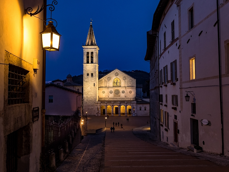 Duomo di Spoleto illuminato di sera visto lungo la scalinata di Piazza del Duomo.