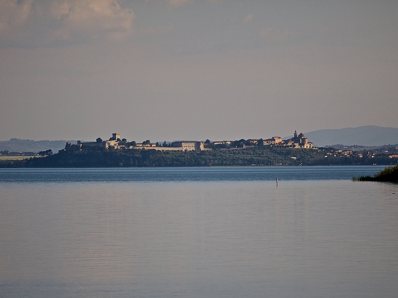 View of Castiglione del Lago in the distance, beyond the calm waters of Lake Trasimeno.