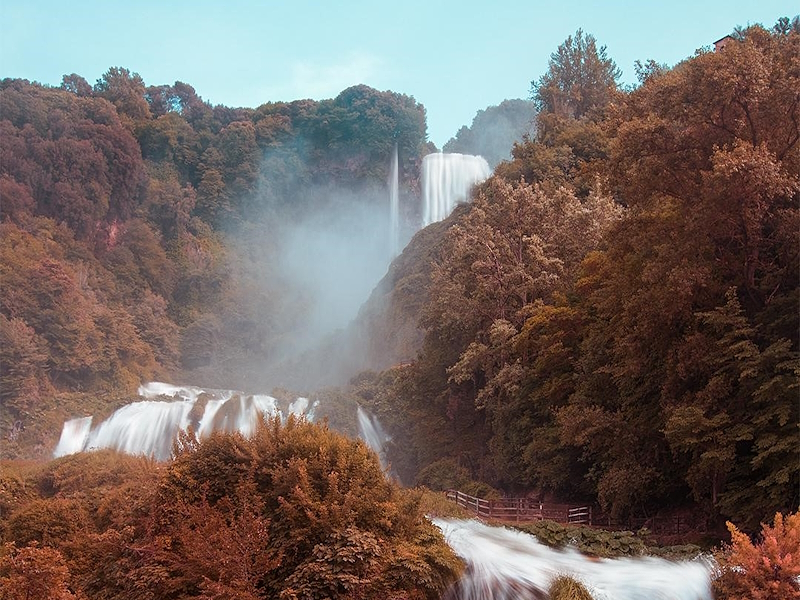 Marmore Falls surrounded by autumn colours, with woodland, cascading water and mist.