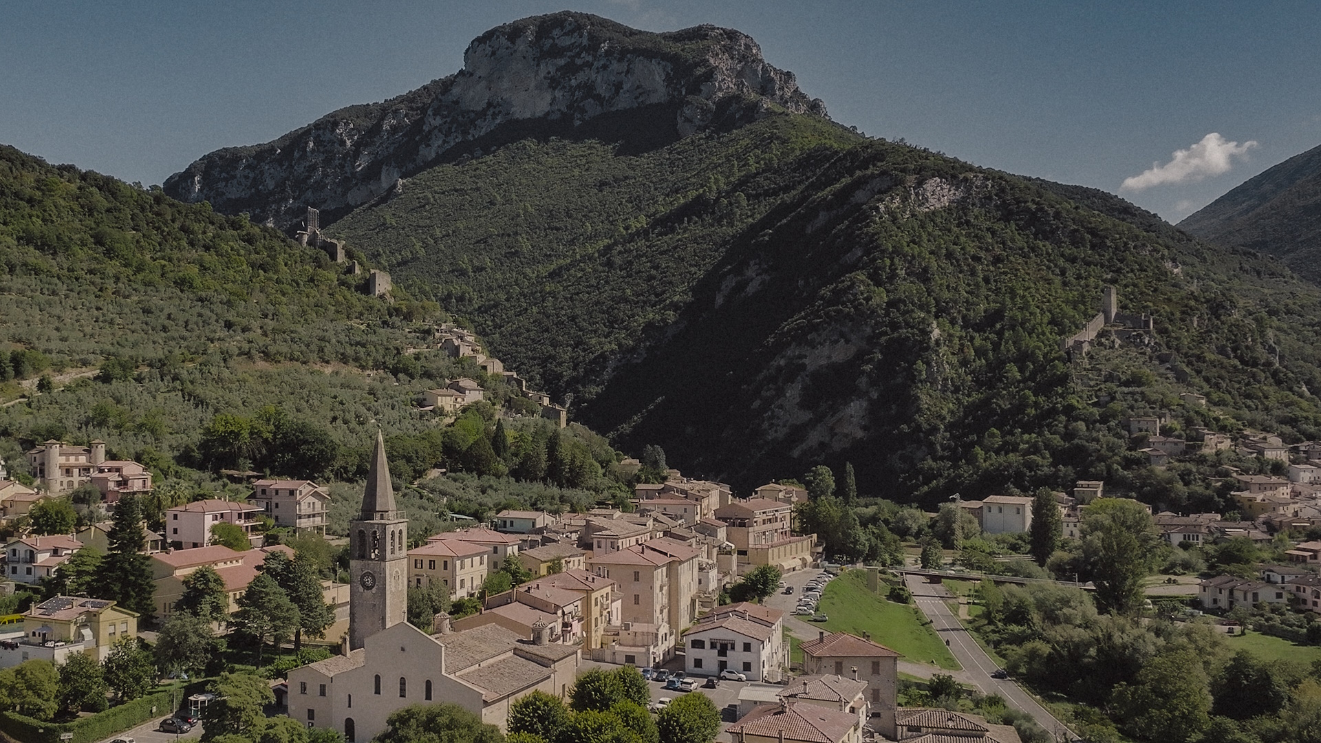 Blick auf Ferentillo am Fuße der Berge des Valnerina-Tals, mit dem Ort, dem Glockenturm und den Festungen an den Hängen.