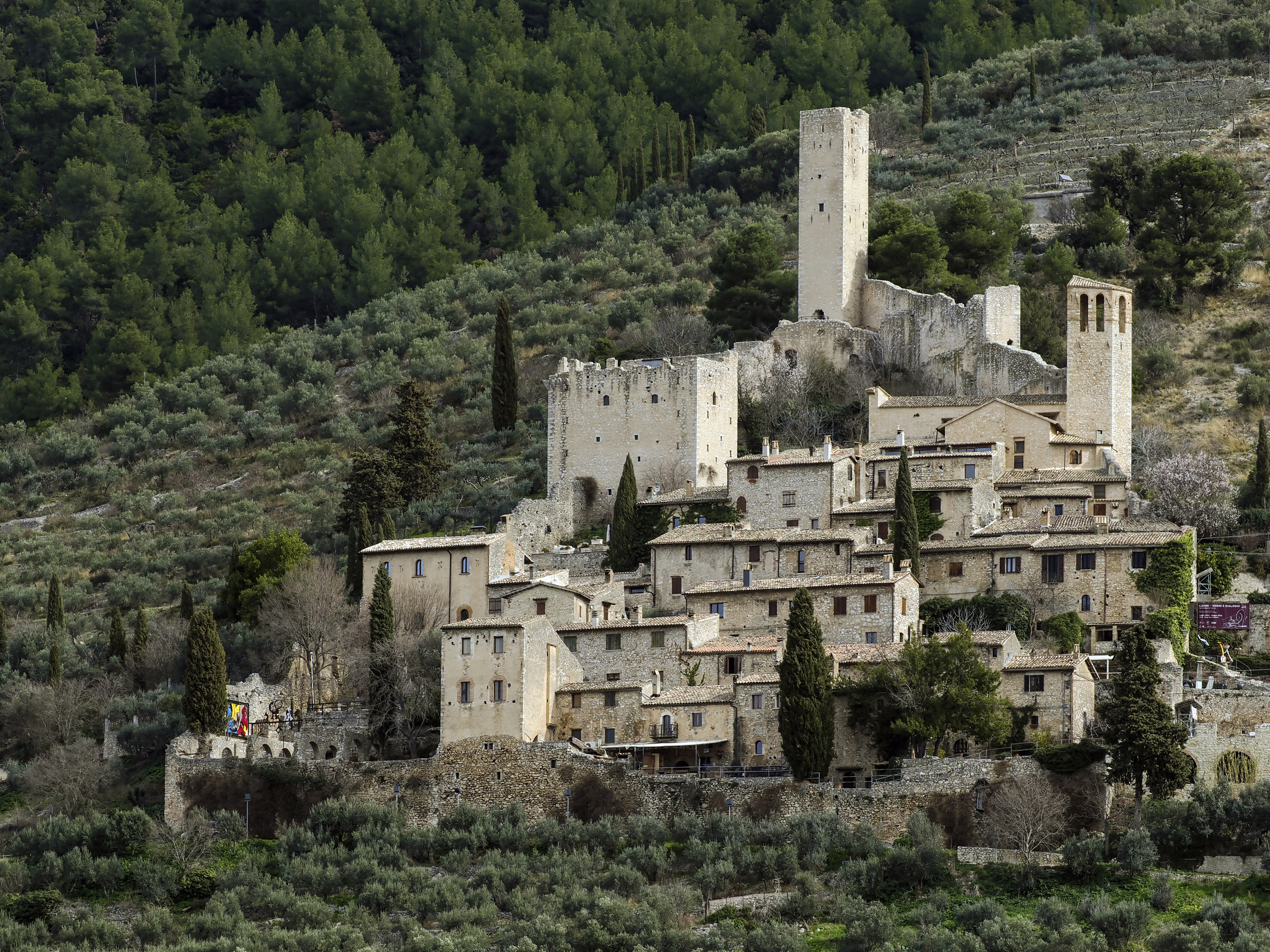 Castle of Pissignano Alto, with medieval towers and stone houses nestled among olive groves and wooded hills
