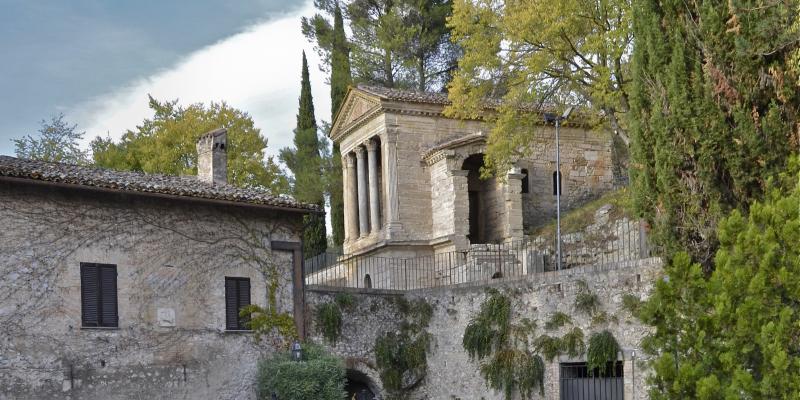 Le Tempietto del Clitunno, un édifice lombard en forme de temple avec colonnes et fronton, entouré de la verdure de la campagne ombrienne