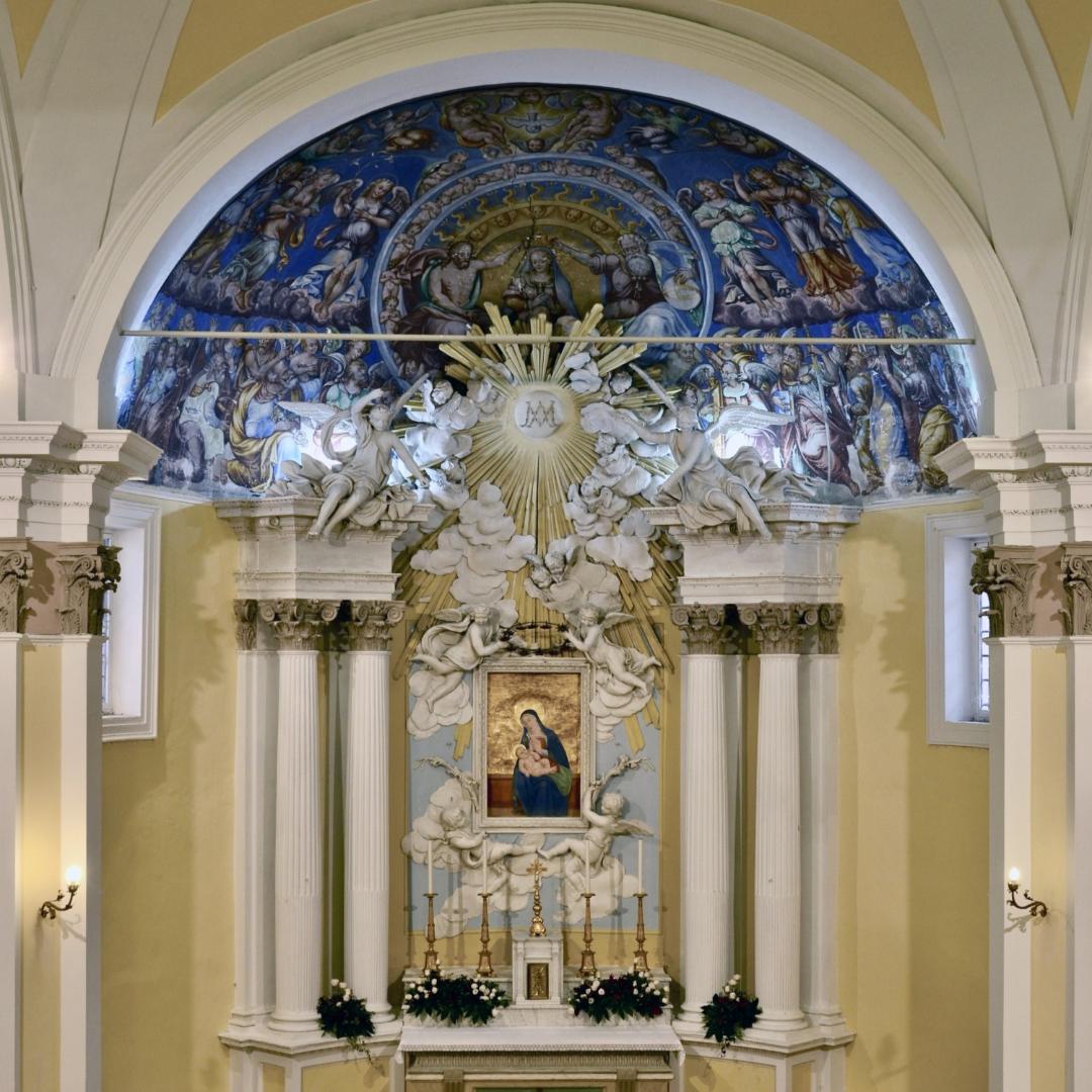 Baroque altar with white columns, statues, and a semicircular fresco in the Church of Madonna della Bianca