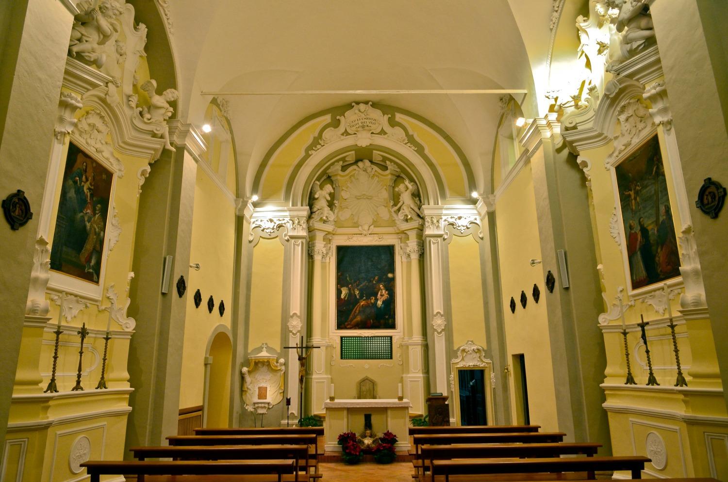 Baroque nave with main altar, white stucco decorations, and side paintings