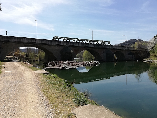 Riverbank with a cycling path and a railway bridge