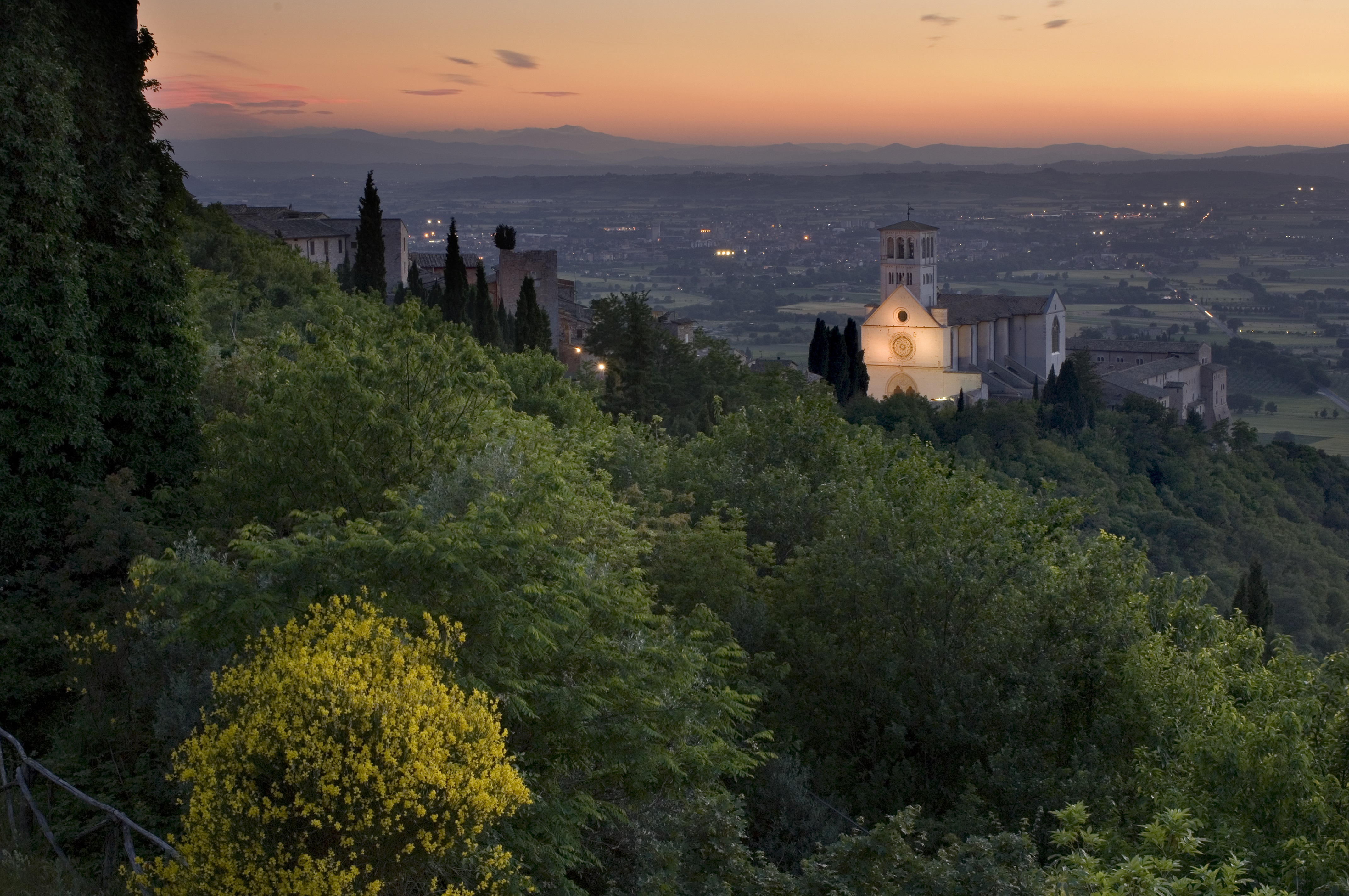 Coucher de soleil sur la ville d’Assise, avec une vue splendide sur la Basilique de Saint François illuminée dominant le paysage.