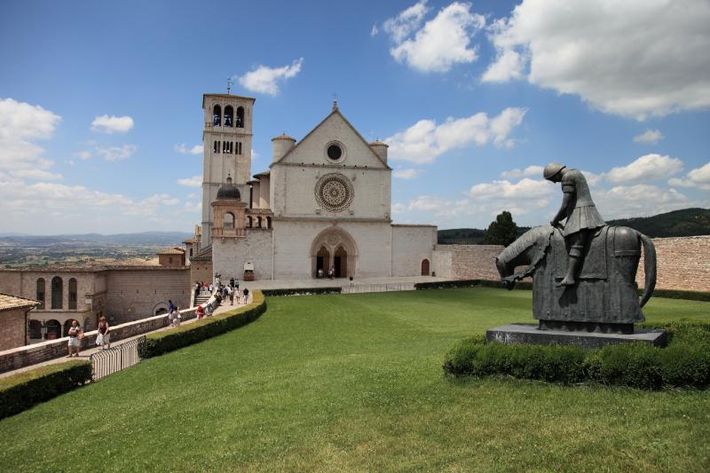 Façade of the Basilica of Santa Maria degli Angeli in Assisi with the square in front and cloudy sky