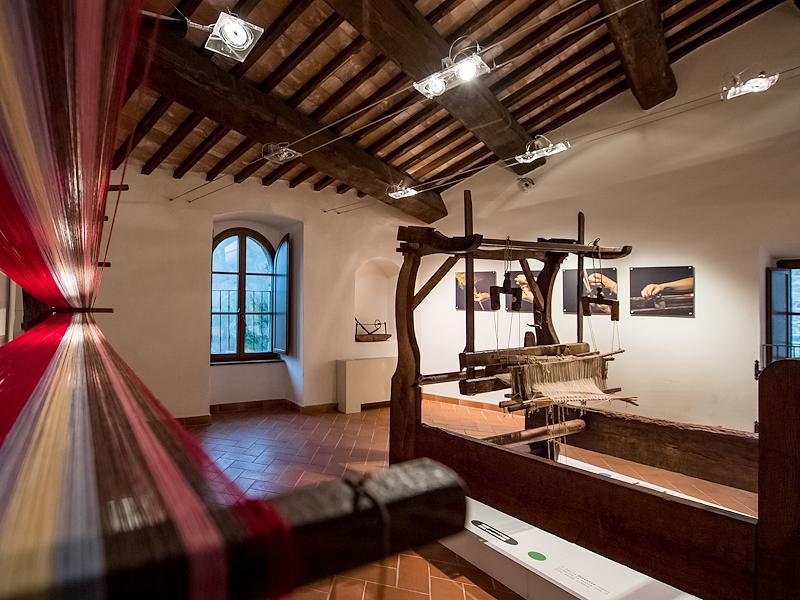 Exhibition hall of the Hemp Museum featuring an antique loom and warping frame with threads of various colors stretched across the pegs in the foreground