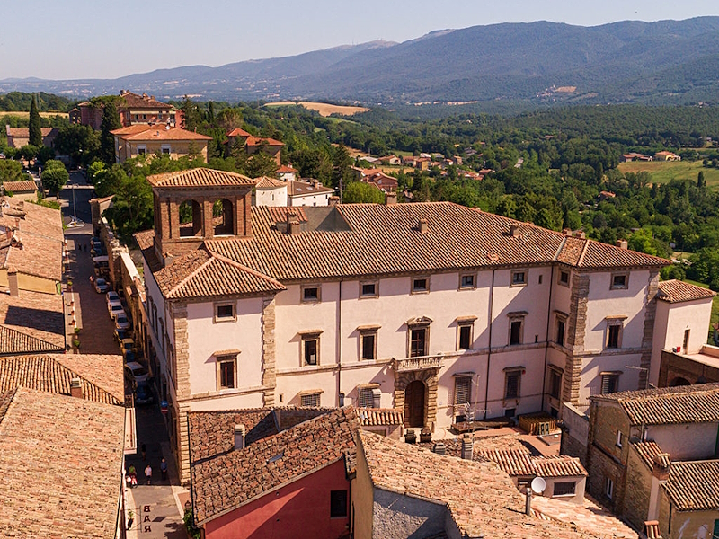 View from above of Cesi Palace among the rooftops of Acquasparta’s historic centre and the surrounding landscape.