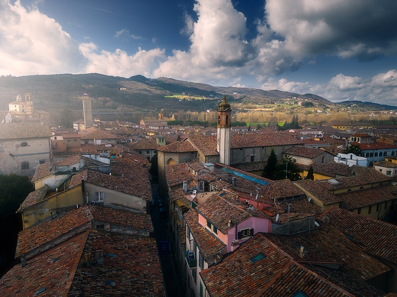 Veduta dall’alto dei tetti e delle chiese di Città di Castello, con colline sullo sfondo e cielo nuvoloso.