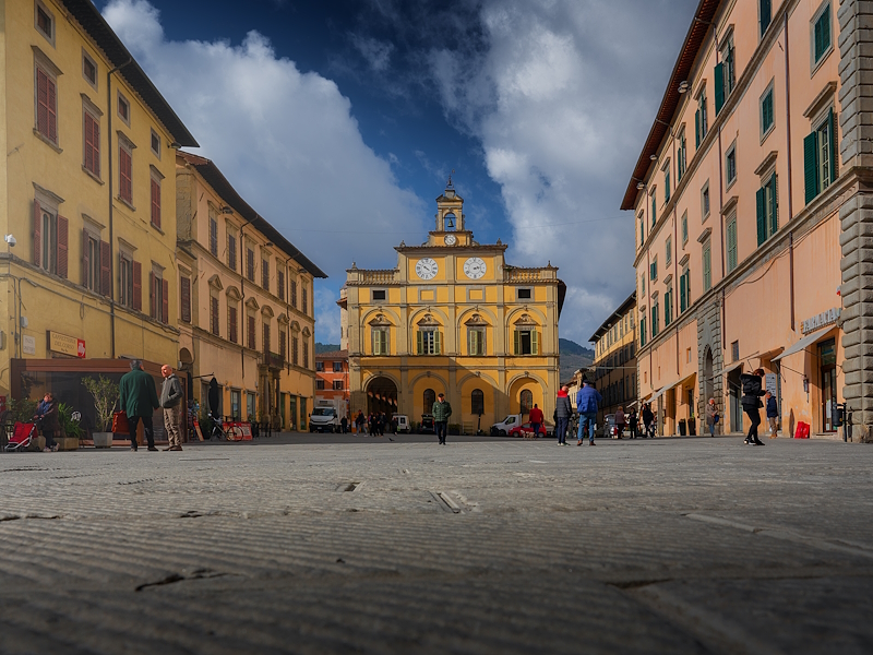 Veduta di Piazza Matteotti a Città di Castello, con il Palazzo del Podestà, edifici storici e passanti.