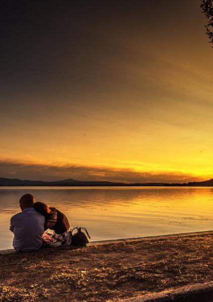 Locandina evento con tramonto sul lago trasimeno sullo sfondo.