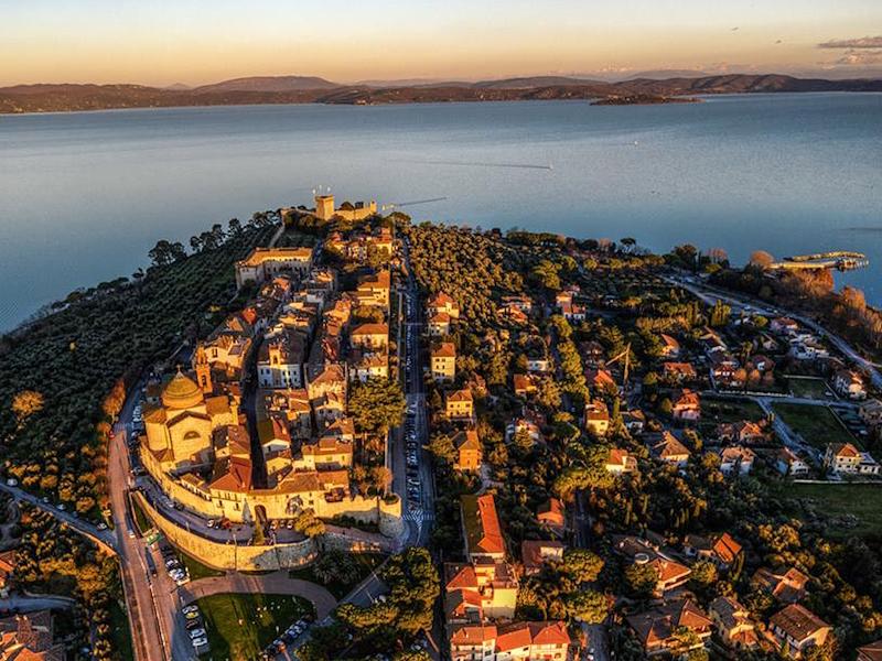 Aerial view of Castiglione del Lago at sunset, with the historic centre overlooking Lake Trasimeno.
