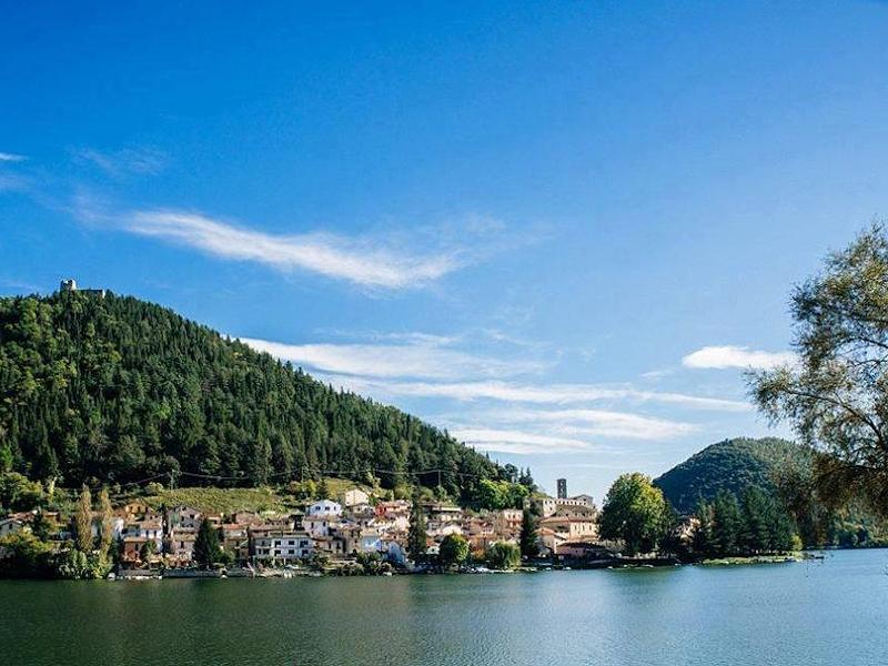 Le village de Piediluco, au pied de la montagne surmontée des vestiges de la forteresse, domine le lac lors d'une journée ensoleillée.
