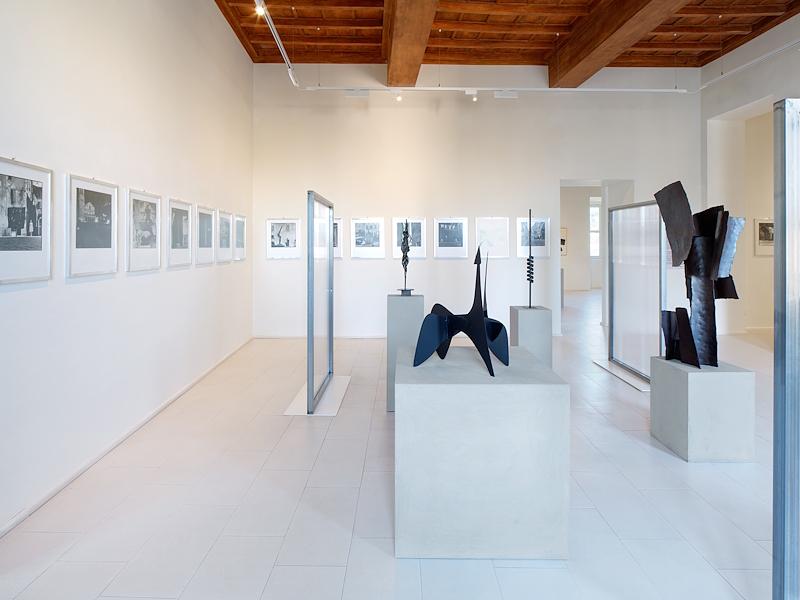 Salle d’exposition du Palazzo Collicola avec des sculptures contemporaines et des photographies aux murs
