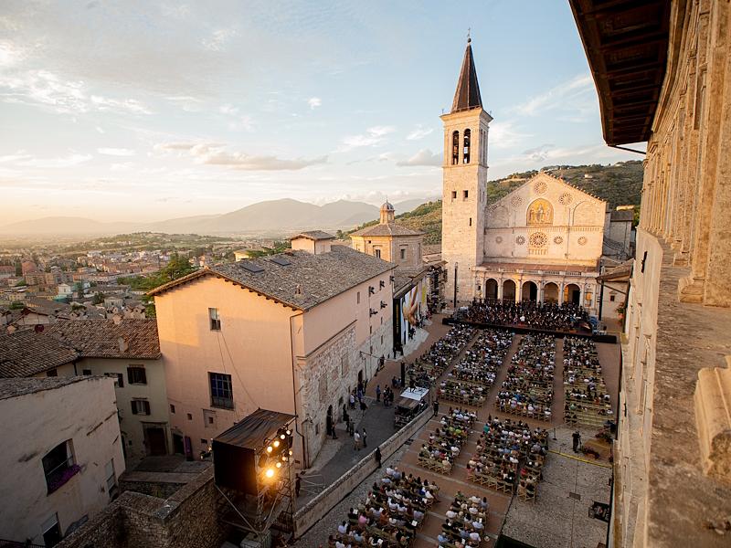 Vue panoramique de la Piazza Duomo à Spolète pendant le Festival des Deux Mondes, avec le public assis devant la scène installée au pied de la cathédrale.